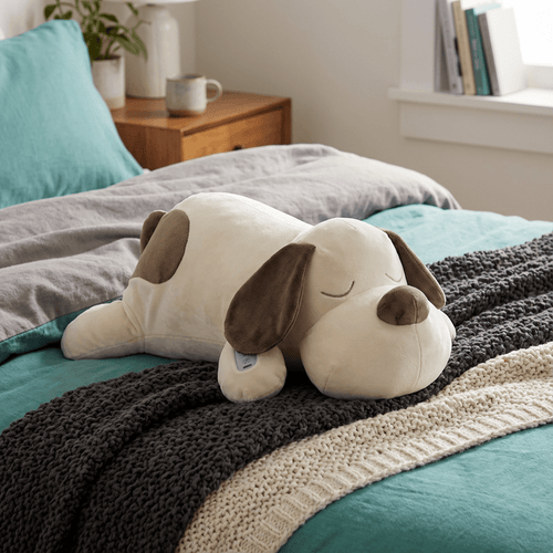 White Noise Animal Plush With Bionic Breathing Dog named CoCo resting on the bed