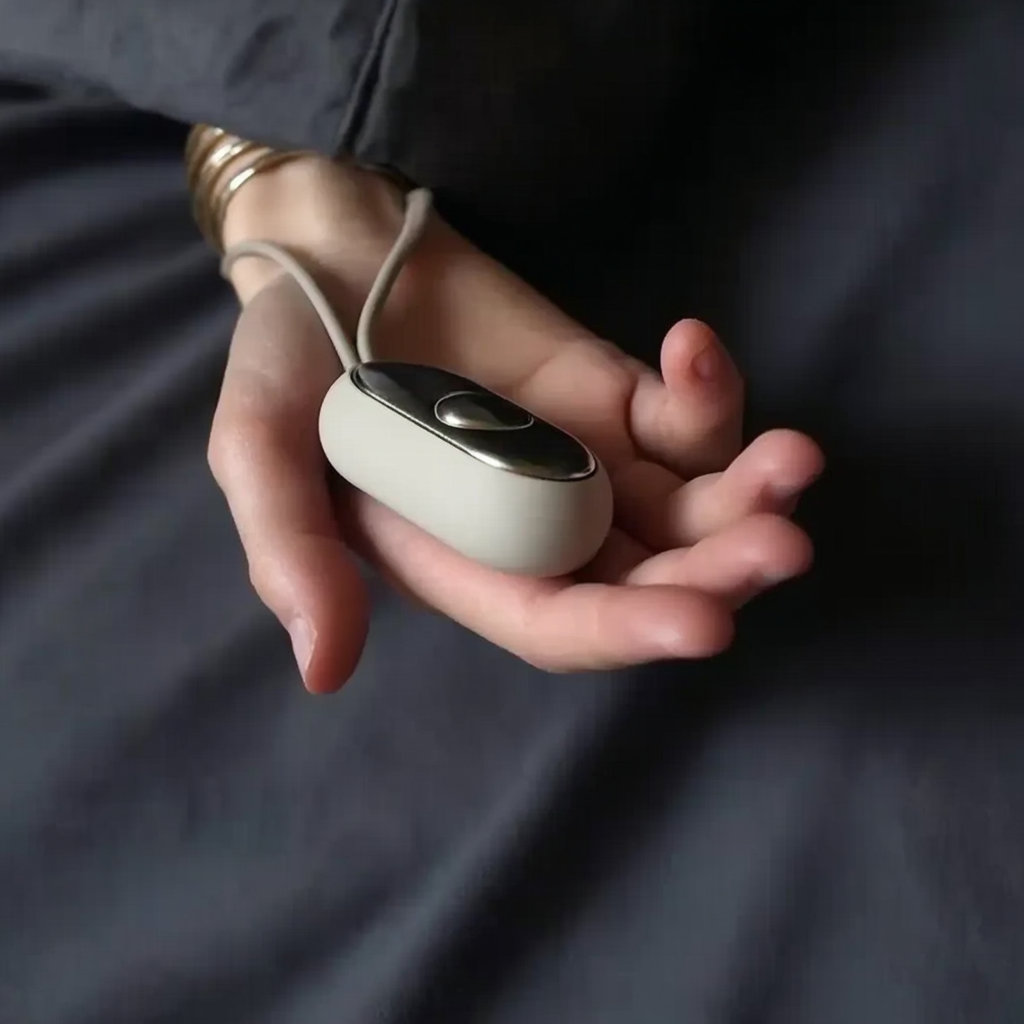 women with navy blue sheets holding silver handheld device which calms your brain ready for bed